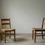 Dos sillas vacías de distinta época frente a frente en un salón