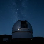 Cúpula de observatorio abierta de noche bajo un cielo estrellado