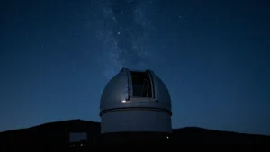 Cúpula de observatorio abierta de noche bajo un cielo estrellado